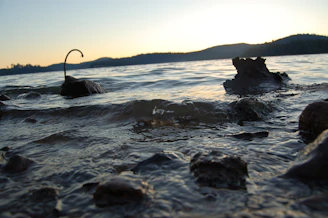 A peaceful lakeside scene at dusk with gentle ripples and distant hills.