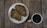 Two croissants are placed on a white plate, accompanied by a cup of coffee on a wooden table.