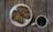 Two croissants are placed on a white plate, accompanied by a cup of coffee on a wooden table.