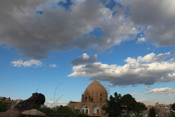 A futuristic translucent dome covering a cityscape under a dynamic sky with storm clouds and sunlight.