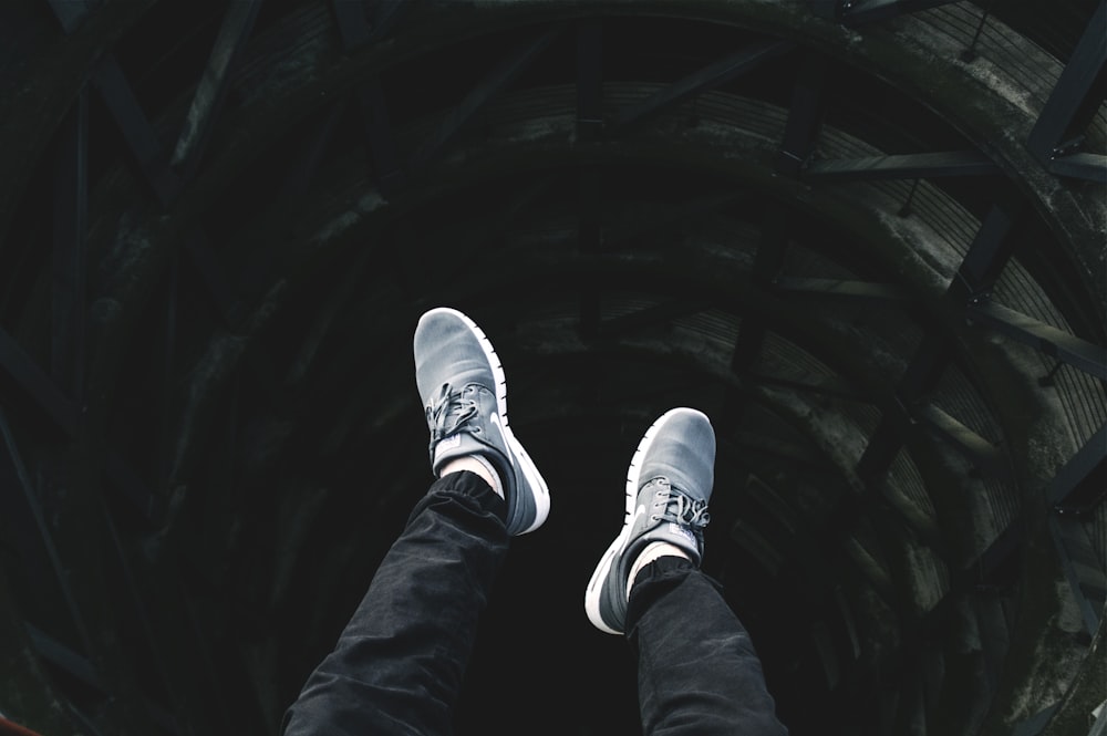 person showing pair of gray lace-up low-top sneakers