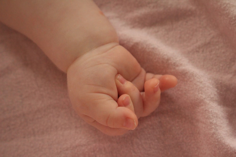 ピンクの毛布の上で赤ちゃんの握りしめた手の接写