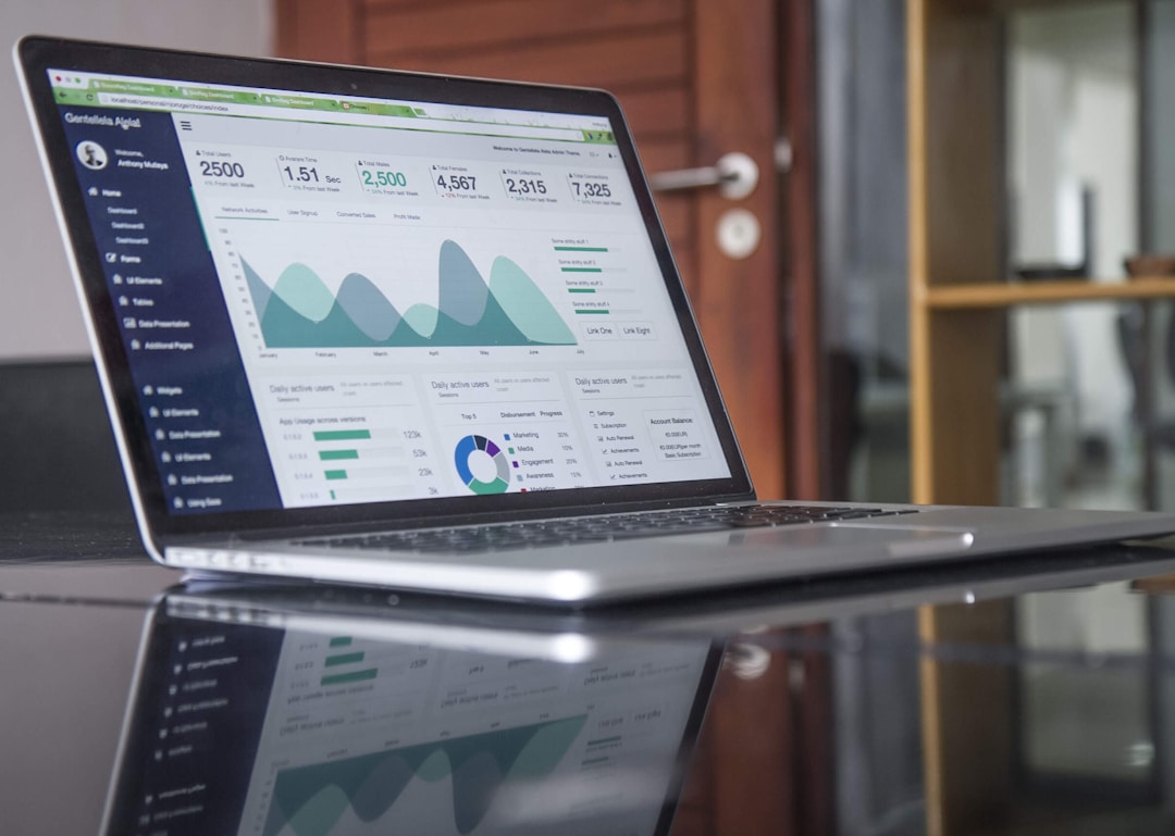 A laptop showing performance dashboards for a company on a reflective table.