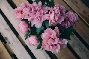 Close-up of a delicate blush peony bouquet resting on a rustic wooden table.