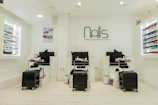 A cozy, elegant nail salon interior with soft lighting and a client enjoying a detailed nail art session.