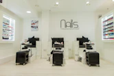 A cozy, elegant nail salon interior with soft lighting and a client enjoying a detailed nail art session.