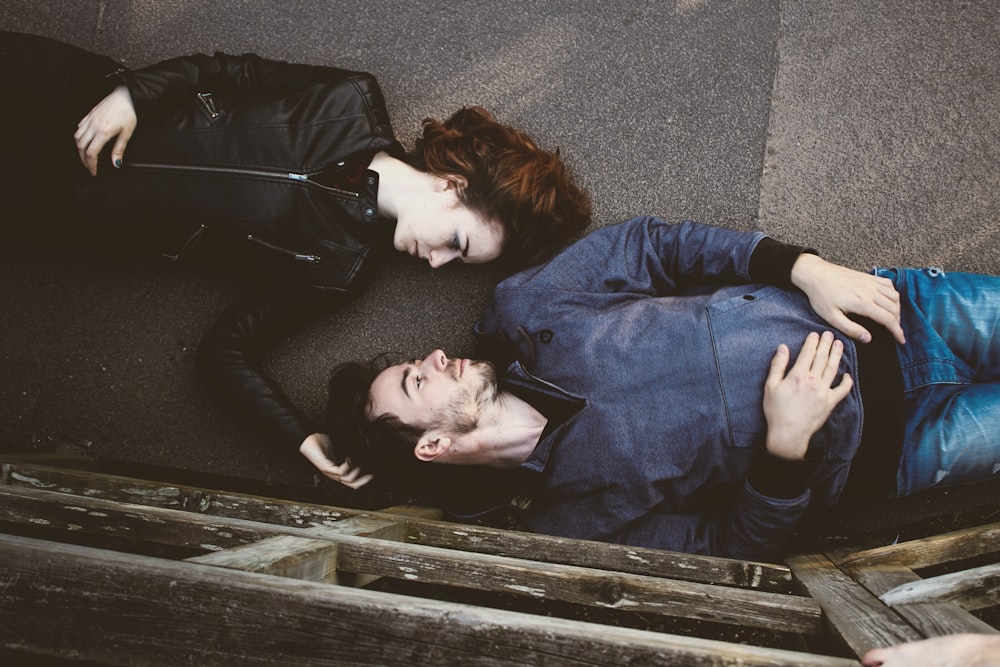 homem e mulher deitados em superfície de concreto cinza olhando um para o outro