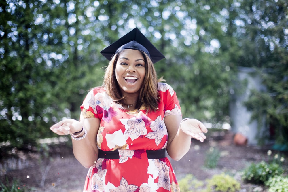 woman wearing academic hat standing in garden showing palm at daytime