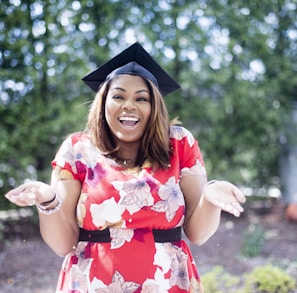 woman wearing academic hat standing in garden showing palm at daytime