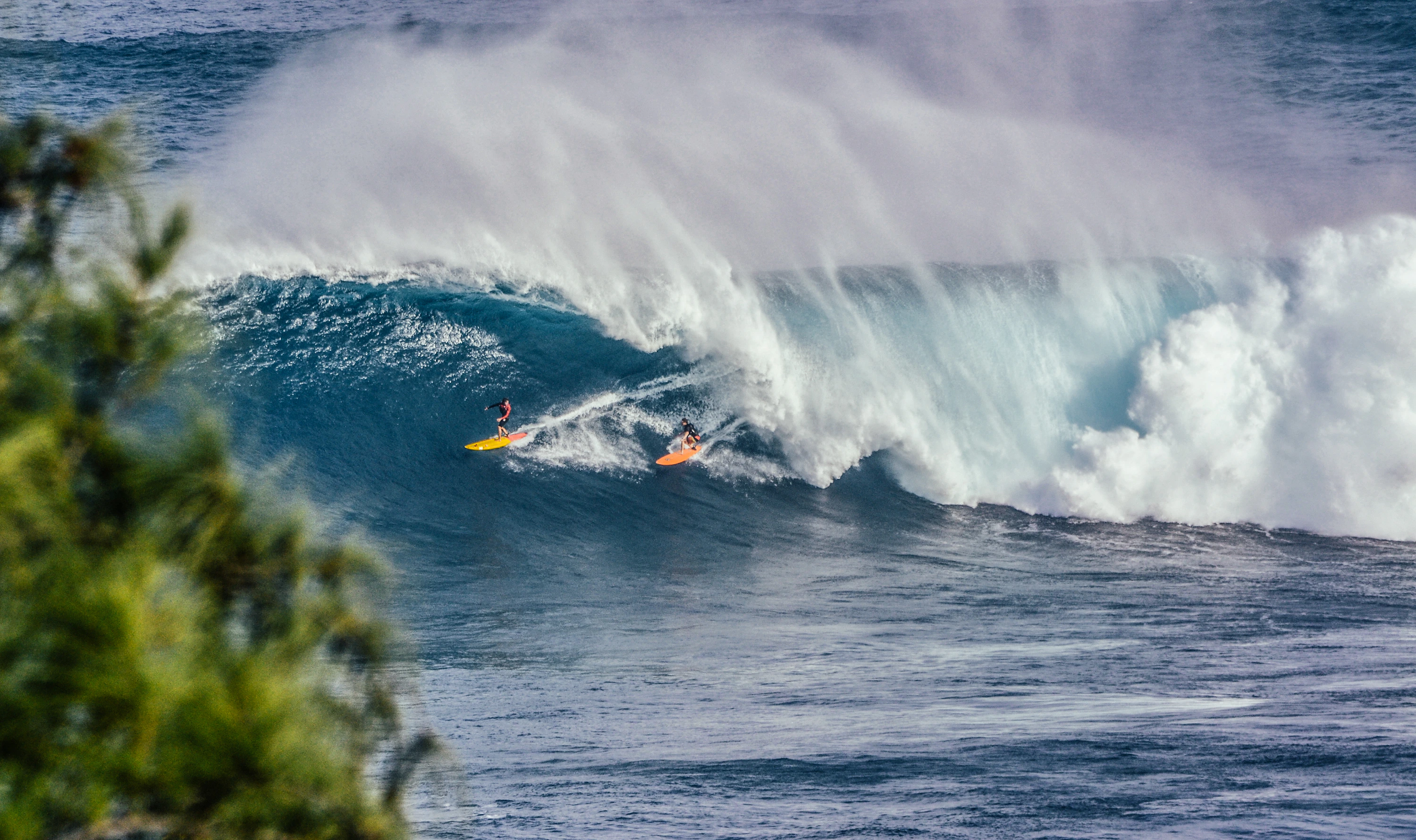 Surfer riding through a powerful blue ocean wave
