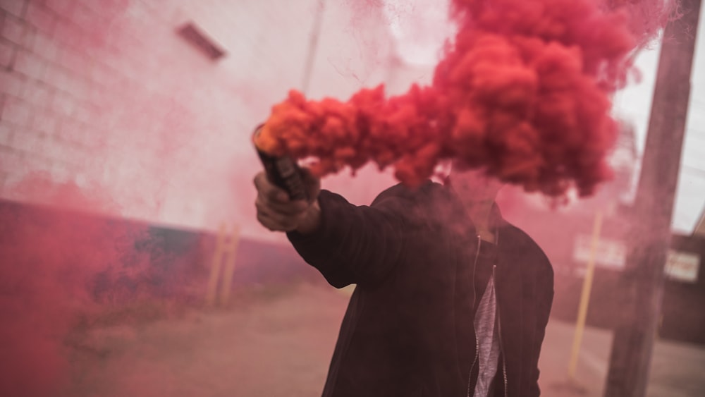 man holding red smoke grenade