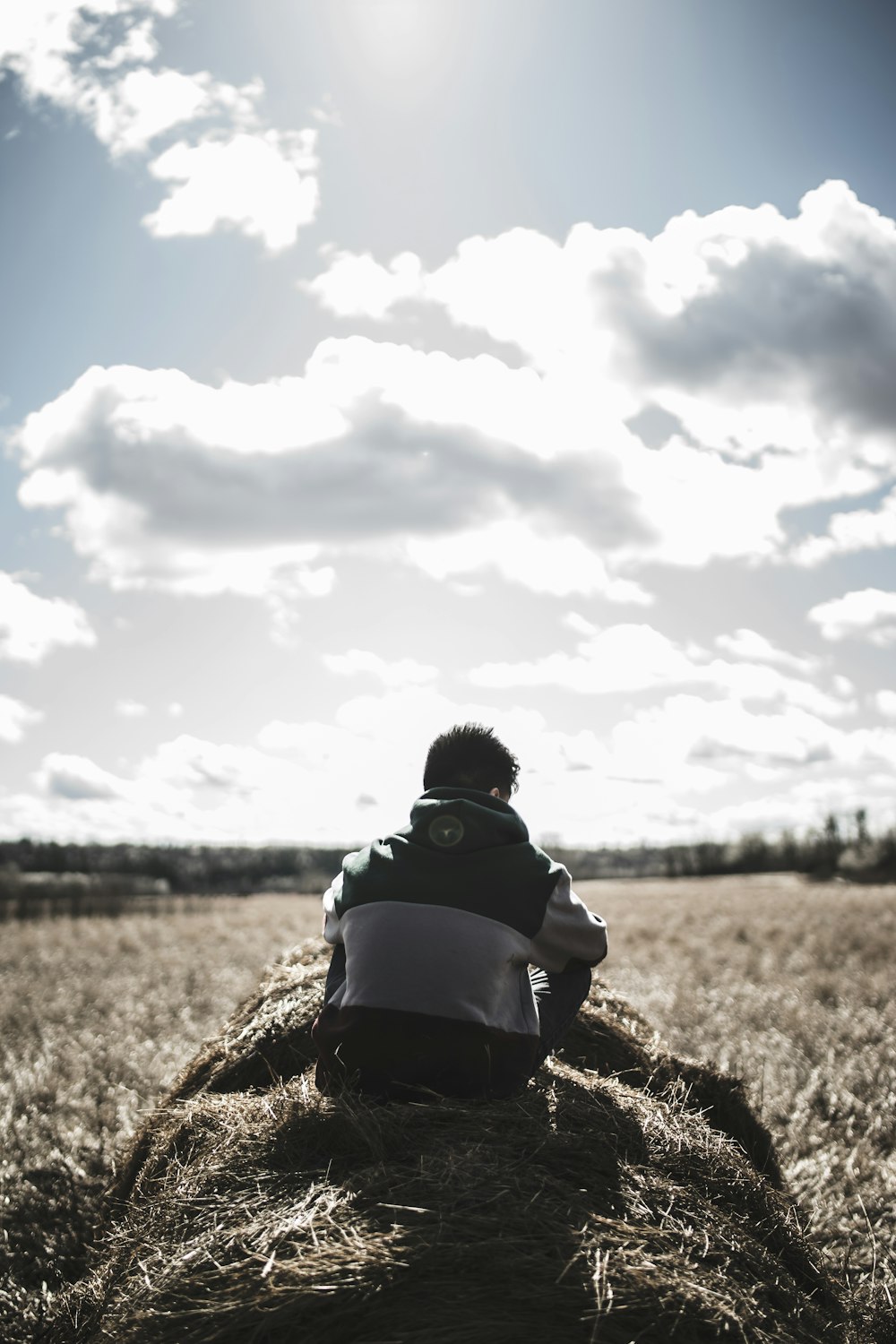 grayscale photography of man siting on hay grass