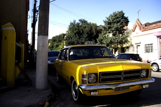 A bright yellow taxi car parked near a popular Kuwait landmark at sunset.