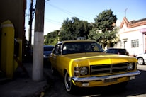 A yellow taxi car waiting in a shaded area near a Kuwait landmark at sunset.