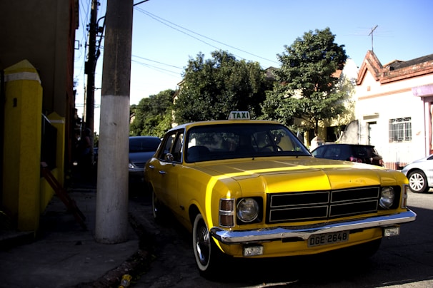 A modern taxi parked outside a cozy home in a small town during sunset.