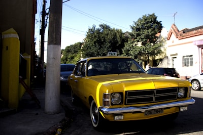 A bright yellow Vila Taxi car parked near the Shopping Boulevard entrance in Rio de Janeiro.