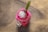 A vibrant smoothie with colorful fruits and tapioca pearls in a clear cup on a wooden table.