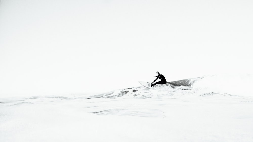 Photographie en niveaux de gris d’une personne surfant