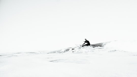 grayscale photography of person surfing in Muriwai New Zealand