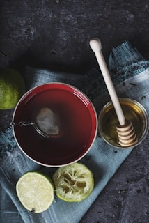 red ceramic bowl filled with water beside lime and honey