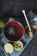 red ceramic bowl filled with water beside lime and honey