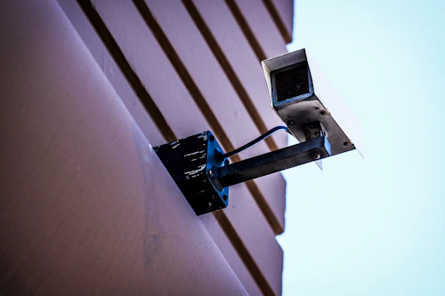 A friendly technician installing a security camera on a sunny Florida home.