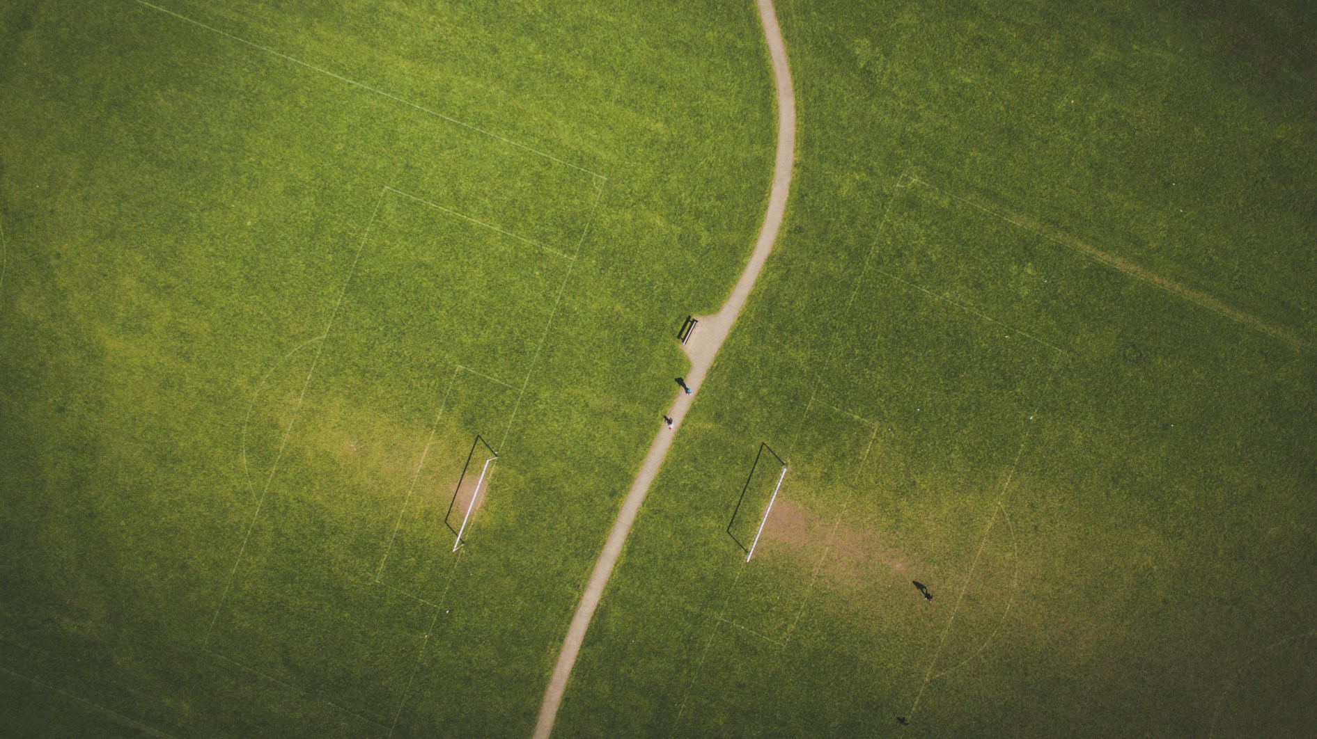 Drone view of dirt road between soccer fields