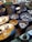 A collection of colorful, intricately designed ceramic dishware featuring artistic patterns and illustrations. The items include plates and bowls with vibrant hues of blue, yellow, and white, and illustrations depicting traditional scenes.