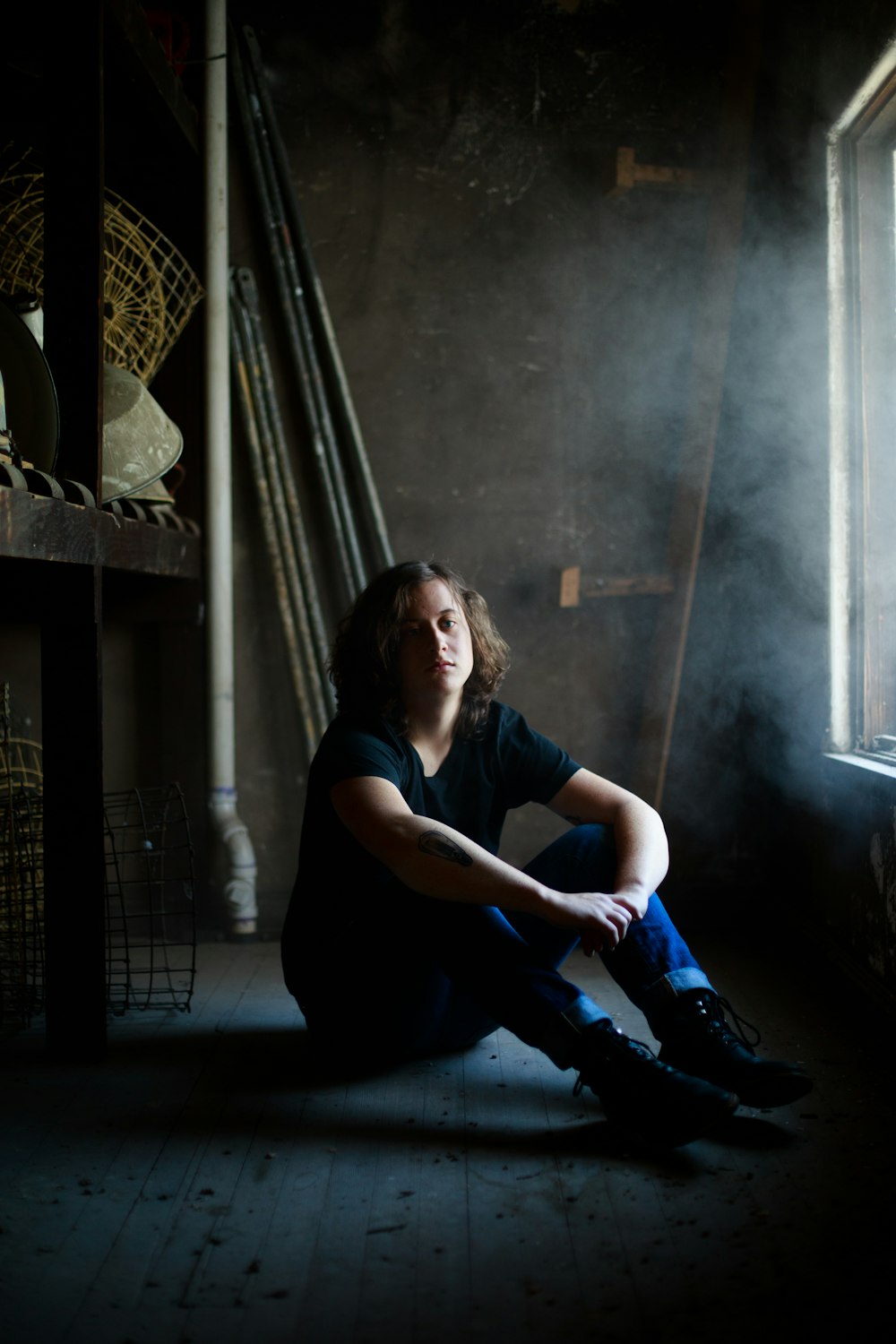 man sitting while resting his arms on his knee inside concrete building