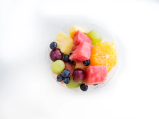 Colorful assortment of fresh fruit mixes in clear bowls on a wooden table