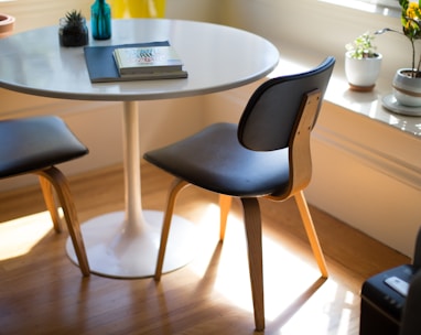 round white dining table beside two chairs on brown hardwood flooring