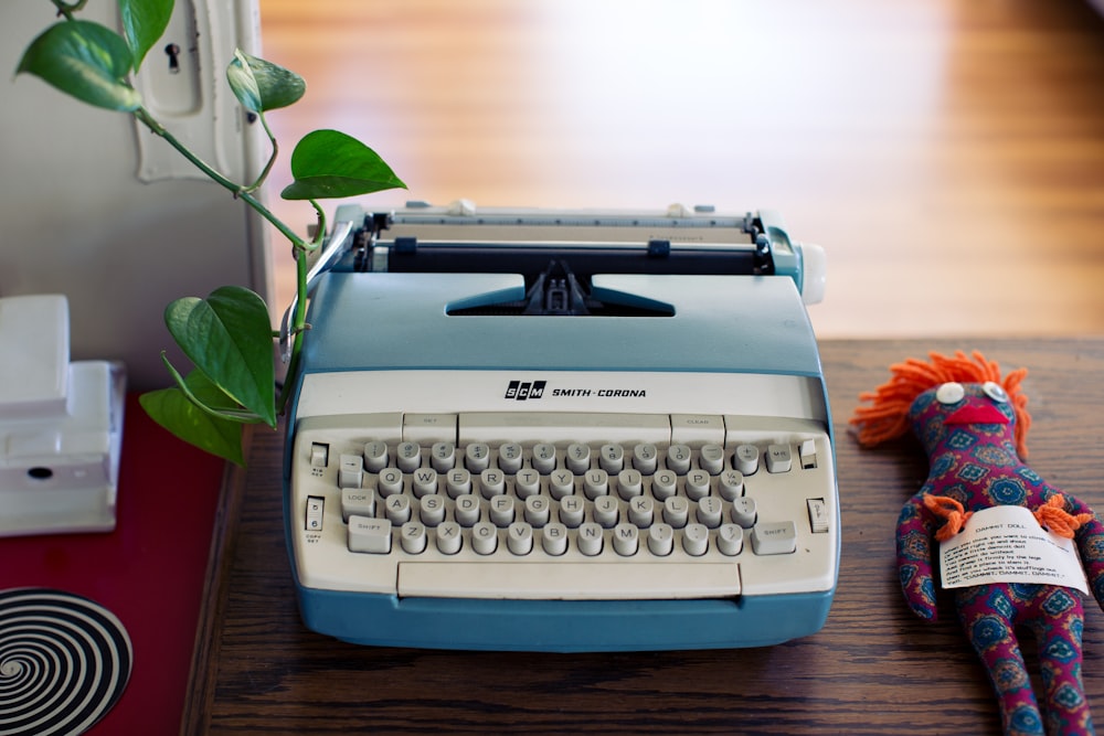 white and beige typewriter and red and black Voodoo doll