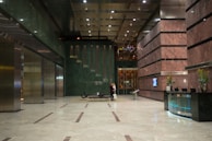 An upscale residential lobby featuring polished stone floors, designer lighting fixtures, and a welcoming concierge desk.