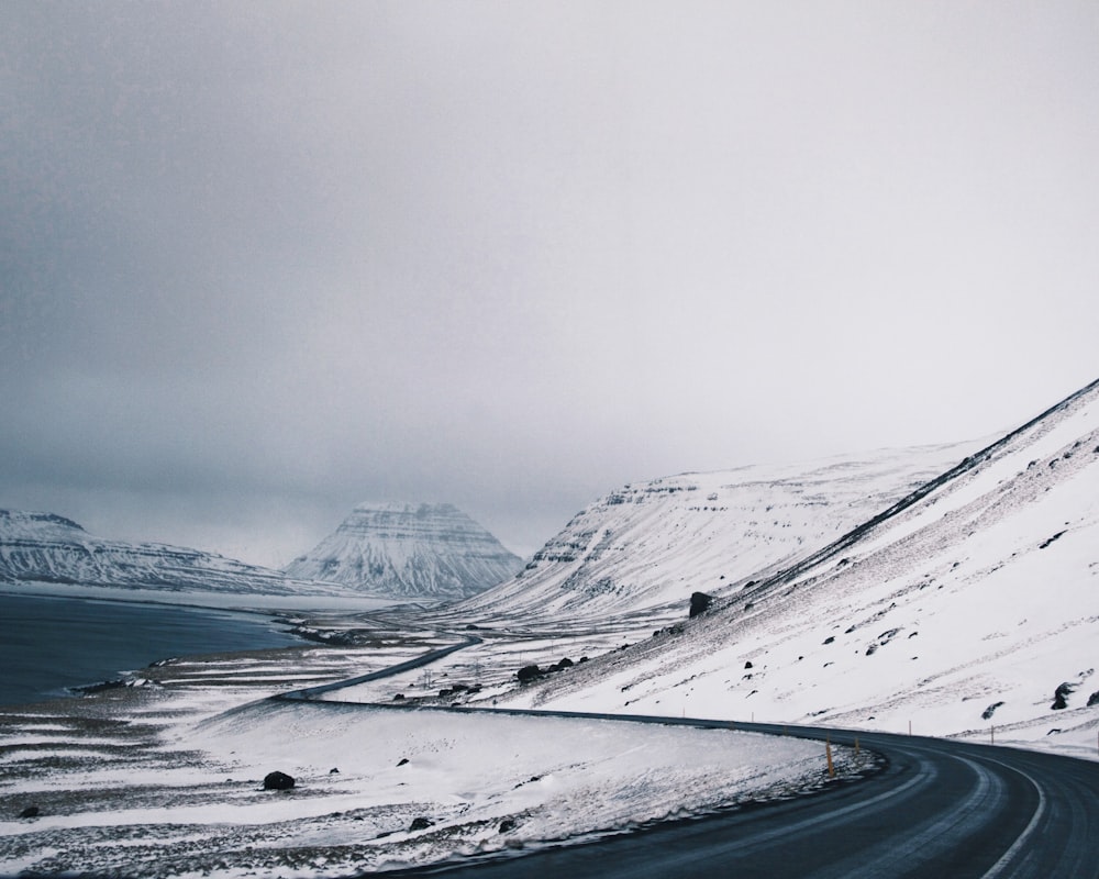 snow covered mountain and body of water at daytime