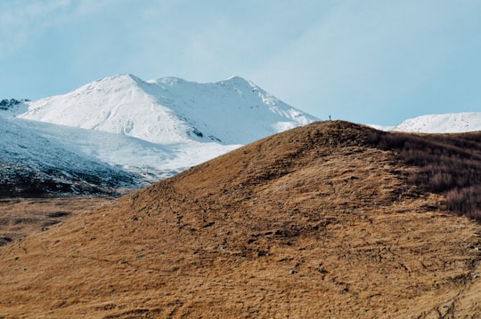 brown mountain near mountain covered with snow in Stepantsminda Georgia