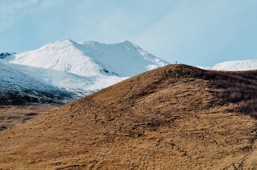 brown mountain near mountain covered with snow