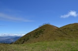 A group pausing on a hilltop overlooking a vast green valley under a clear sky.