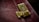A close-up of a polished gold combination lock attached to a distressed, dark red leather surface, likely part of a briefcase or similar item.