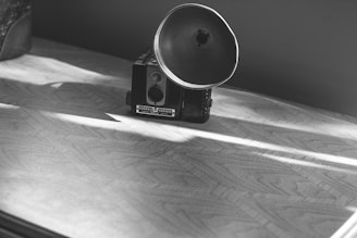 A close-up of a vintage medium format camera resting on a wooden table bathed in soft natural light.