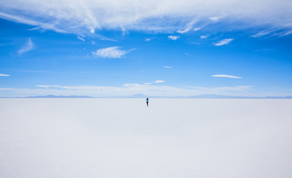 persona che cammina sul campo coperto di sabbia durante il giorno