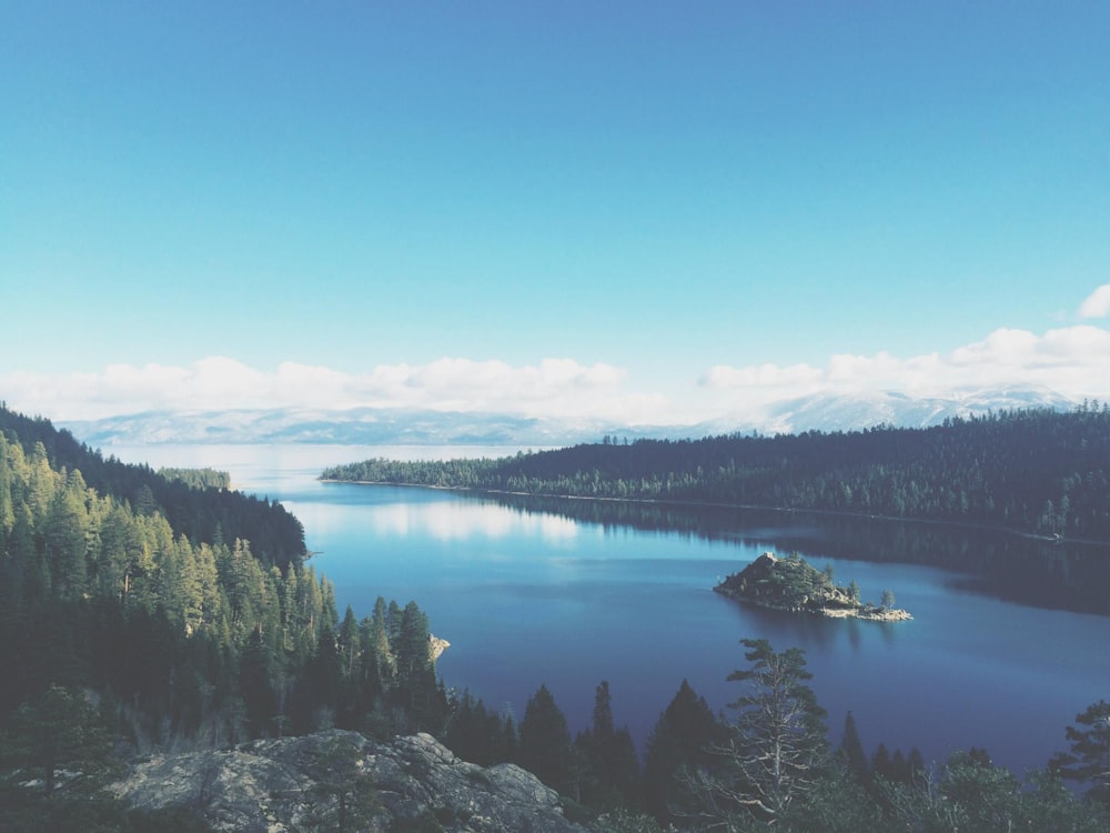 lake surround by mountains and trees under blue sky