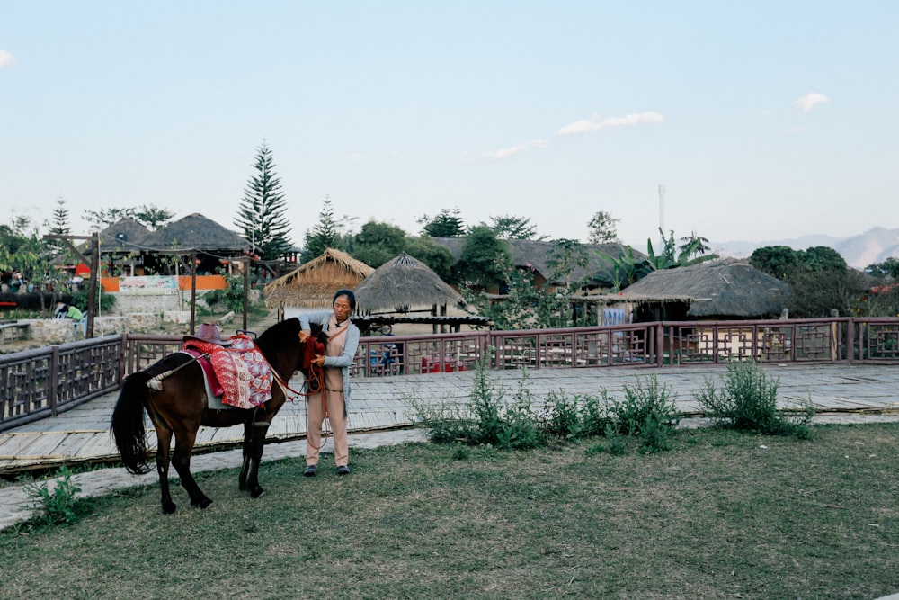 woman holding black horse beside fence