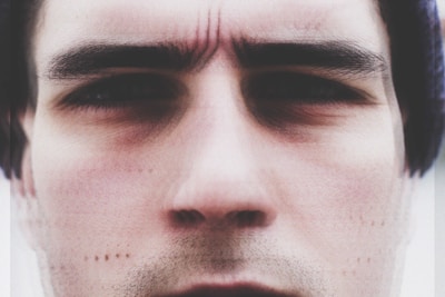 A close-up of a human face with furrowed brows, showing signs of concentration or concern. The image is slightly blurred around the edges, adding a sense of softness.