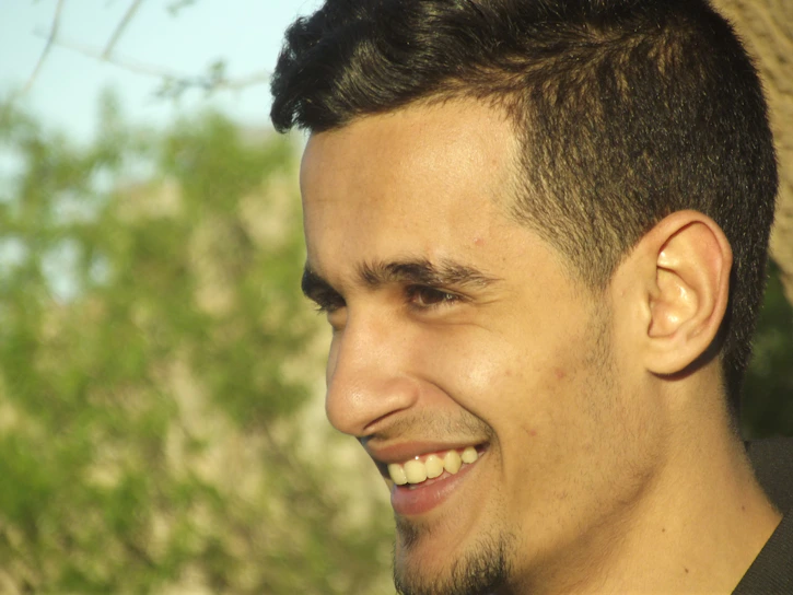 A softly blurred profile photo of a smiling young man in casual attire, hinting at warmth and approachability.