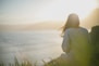 woman wearing gray long-sleeved shirt facing the sea