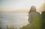 woman wearing gray long-sleeved shirt facing the sea