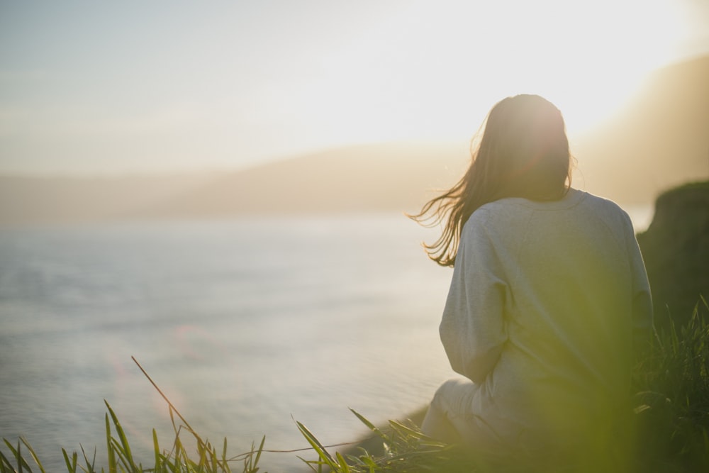 donna che indossa una camicia grigia a maniche lunghe di fronte al mare