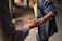 Two people are gently holding hands, suggesting a moment of connection or support. One person is wearing a denim shirt and bracelets, and the setting appears to be casual and intimate.