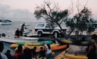 A family unloading kayaks from a Dockside Outfitters delivery truck at a sandy beach launch.