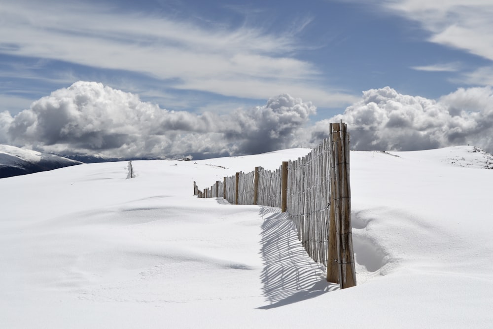 cerca de madeira marrom no campo de neve sob nuvens cinzentas